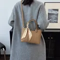 Retro camel lychee leather bucket bag with houndstooth silk scarf on model's shoulder - Khaki