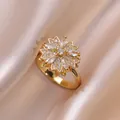 Dettaglio macro di anello a fiore dorato con zirconi bianchi su sfondo di seta - Anello in Zirconia Rotante (J0202)
