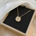 Detailed view of a gold clover necklace featuring four heart-shaped crystals in a jewelry box - Gold White
