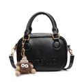 Chic black leather handbag with bronze buckles and a cute plush monster charm - Black