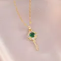 Collier clé fleur dorée élégant avec zircon émeraude sur fond en satin violet - Vert