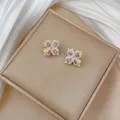 Macro view of four-leaf clover stud earrings with purple heart crystals and white zircons - Purple Rotating Earrings
