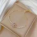 Detail of adjustable gold bracelet with purple clover pendant and white zircon stones - TS0525 Purple Bracelet