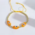 Detailed shot of yellow Evil Eye beads and gold beads on a handmade braided cord bracelet - Orange
