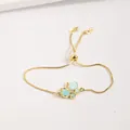 Détail macro du bracelet ajustable doré avec breloque papillon bleu et zircons étincelants - Bleu clair