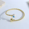 Twisted rope 18K gold plated open bangle featuring a blue evil eye bead and gold ball - White