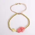 Detail of 18K gold beaded bracelet with sacred heart and cross charms on white background - Rose Red