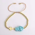Detalle de pulsera de cuentas con corazón sagrado azul y cruz dorada en cordón - Azul lago