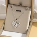 Close-up of heart pendant necklace with shimmering crystals in a gold gift box - Hand Holding Protection Style (X4016) / Steel