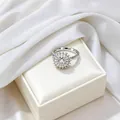 Detailed view of silver sunflower ring with shimmering zircon petals on white leather case - Spinner Ring / Steel