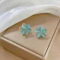 Dettaglio degli orecchini a fiore blu con inserto in zircone su portagioie beige - Orecchini Blu