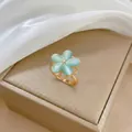 Macro view of gold flower ring with blue cat-eye stone petals and micro-pave zircons - Blue Rotating Ring (Alt)