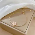 Dettaglio del bracciale a fiore dorato regolabile con petali rosa e zirconi cubici - Braccialetto Rotante Bianco