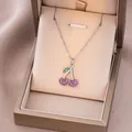 Détail du collier pendentif cerise avec zircon rose dans un écrin de luxe champagne - Couleur Acier Cerise Colorée