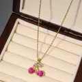 Gold cherry pendant necklace featuring pink heart gemstones and zircons in a jewelry box - Pink Heart Gemstone Cherry (X2610)