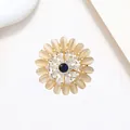 Macro view of sunflower brooch featuring yellow cat eye stones and a deep blue gemstone - Xx0043
