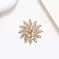 Macro shot of layered gold snowflake brooch with zircon crystal petals on white background - Xx0147