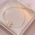 Dettaglio del bracciale tennis dorato regolabile con pietre rosa a cuore e ciondolo a fiore - Cuore Rosa e Viola (TS0404) / Cuore