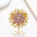Macro shot of spinning flower brooch with purple zircon petals and golden metal finish - Xx0196