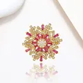 Macro detail of golden snowflake brooch with rose red crystals and shimmering pavé zircons - Xx0205