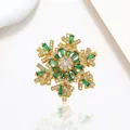 Close-up of golden snowflake brooch with green gemstones and micro-pave crystals - Xx0208