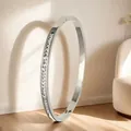 Detail of silver stainless steel bangle with square zircon pavé setting on wood floor - Single Row Square Diamonds (29-D-12) / Steel