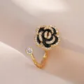 Elegante anillo de camelia con esmalte negro y circonitas sobre fondo de seda champán - Anillo Camelia