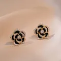 Elegantes pendientes de camelia dorados con esmalte negro y detalles de circonita blanca - Pendientes Camelia