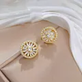 Dettaglio di orecchini a lobo a girasole dorati con zirconi su espositore beige - Orecchini a Bottone Girasole (E0393 Orecchini Color Oro)