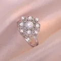 Elegant rotating flower necklace with zircon and pearls on champagne satin background - Steel Rotating Flower Ring (J00339)