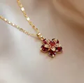 Macro detail of rotating flower necklace with red zircon petals and gold sequin chain - Red Flower Necklace
