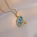 Vue macro du pendentif en forme d'éventail doré avec zircons bleu clair brillants - Collier Éventail en Zircon / Or / Bleu Ciel