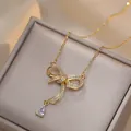 Elegante collar de lazo dorado con circonitas y colgante de gota en caja de joyería - Collar de Lazo de Zirconia (X1844)
