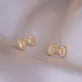 Elegante goldene Schleifen-Ohrringe mit Zirkon-Steinen auf silbernem Seidenhintergrund - Schleife Ohrringe (E390)