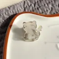 Detail of a cat-shaped acetate hair claw clip on a white ceramic tray with soft lighting - Smoke