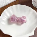 Gros plan sur une pince à cheveux nœud rose translucide avec des paillettes d'or - Violet