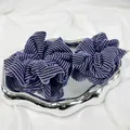 Lot de deux chouchous tricotés à rayures violettes et noires sur un plateau argenté - Petit Choucou