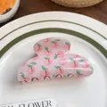 Dettaglio del mollettone rosa con stampa di pesche su un piatto di ceramica bianca - Pesca / Rosa