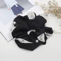 Detalle de un coletero de satén negro con malla de flores y delicadas perlas blancas - Negro