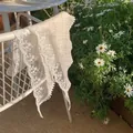 White lace triangular headscarf with hollow embroidery and pom-pom trim in a garden setting - Off White