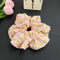 Chouchou floral rose avec motifs verts et violets sur fond texturé sombre - Vert à Pois