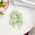 Detalle de un coletero de tela a cuadros verdes con lazo y elegante perla blanca - Coletero con Cinta