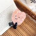 Molla per capelli a cuore marmorizzato rosa con faccina e piedini su un libro aperto - Cuore Rosa