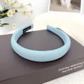 Diadema acolchada de tejido azul claro con etiqueta artesanal sobre un libro - Azul Cielo