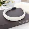 Diadema de esponja tejida beige con etiqueta artesanal sobre libros de café - Beige