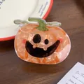 Close-up of marble orange acetate pumpkin hair claw clip with a black Jack-o'-lantern face - Smiling Pumpkin