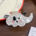 Detailed shot of a marble-textured ghost hair claw clip with red hearts on a vintage plate - Winged Ghost