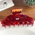 Détail d'une pince à cheveux bordeaux marbrée avec strass et motif de visage rigolo - Personnage Drôle Rouge Vin