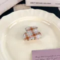 Mini haarklem met bruin en blauw ruitpatroon op een elegant crèmekleurig bord - Plaid Kleine Stijl