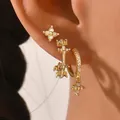 Macro shot of gold geometric earrings set with white gems worn on ear for styling - Shell White Style (AEH70352-4)